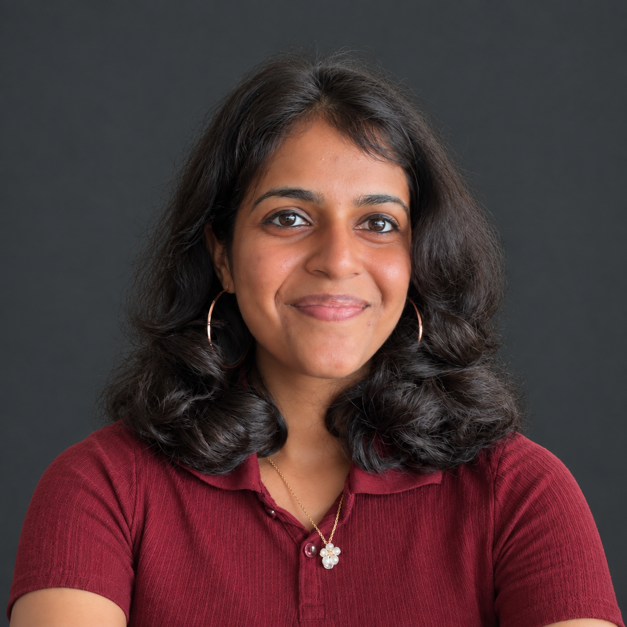 Portrait of Pooja Ravi against a charcoal background